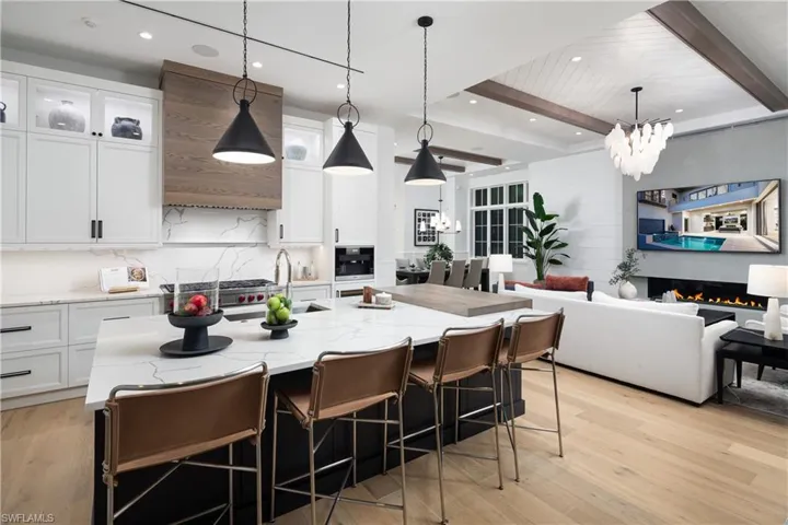 Kitchen featuring white cabinets, recessed lighting, light stone countertops, open floor plan, and a center island with sink