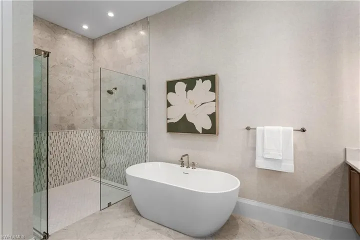 Full bath featuring a freestanding bath, vanity, a stall shower, recessed lighting, and marble finish floors