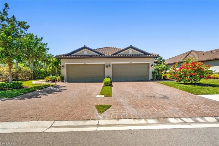 View of front of property with a tiled roof, a garage, driveway, and stucco siding