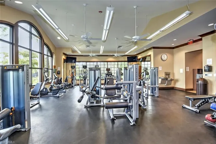 Exercise room featuring high vaulted ceiling, baseboards, crown molding, and a ceiling fan