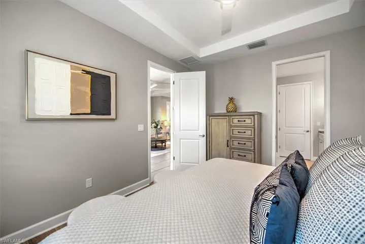 Bedroom with a raised ceiling, baseboards, and visible vents