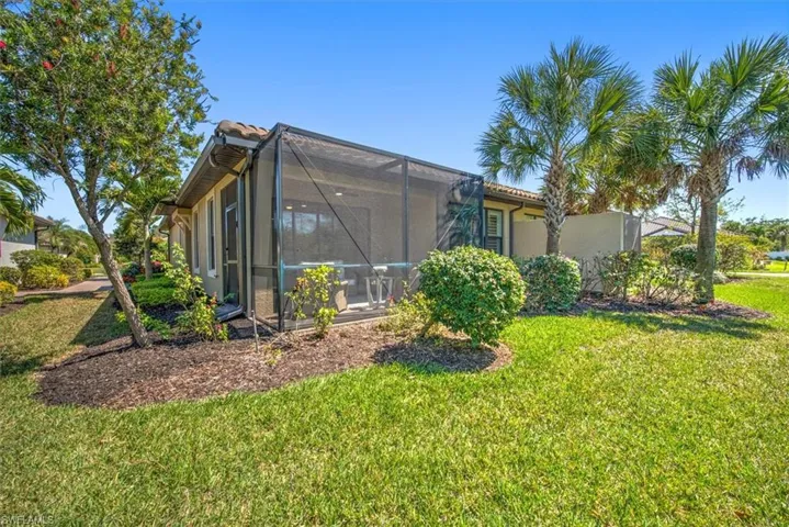 View of home's exterior with glass enclosure, a tile roof, a yard, and stucco siding