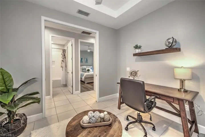 Home office with light tile patterned flooring, visible vents, and baseboards