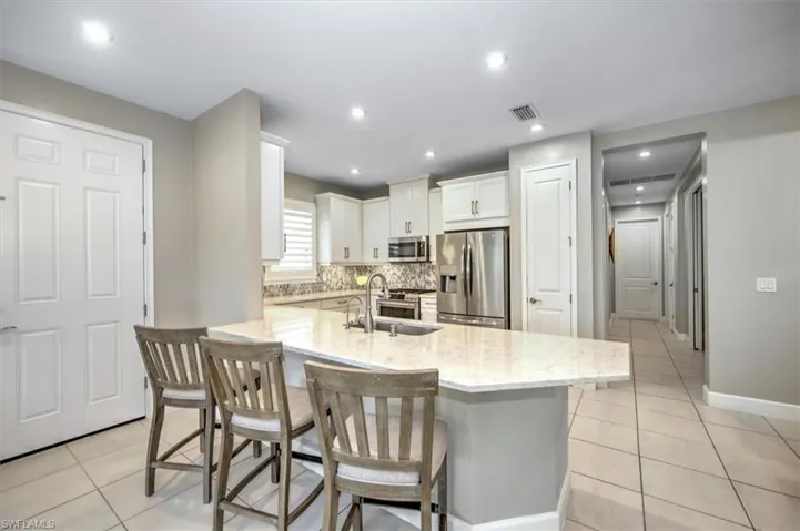 Kitchen with a sink, light tile patterned floors, light stone countertops, and stainless steel appliances
