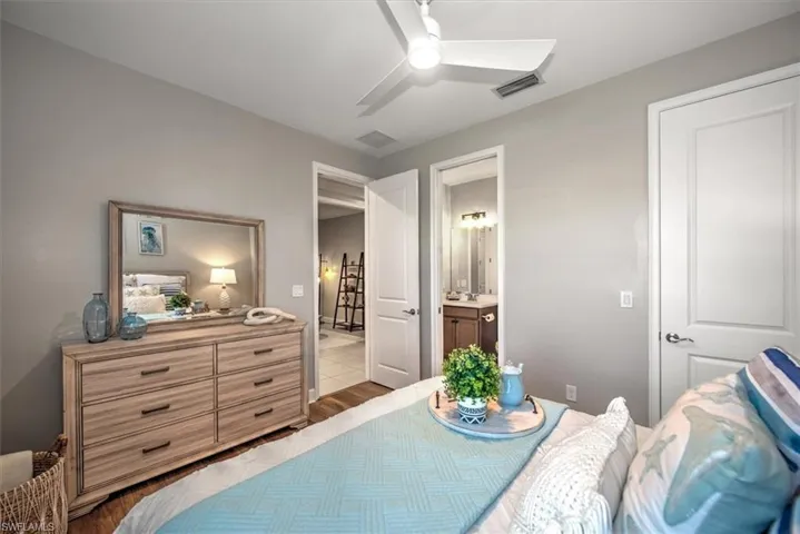 Tiled bedroom featuring visible vents, ensuite bathroom, and ceiling fan