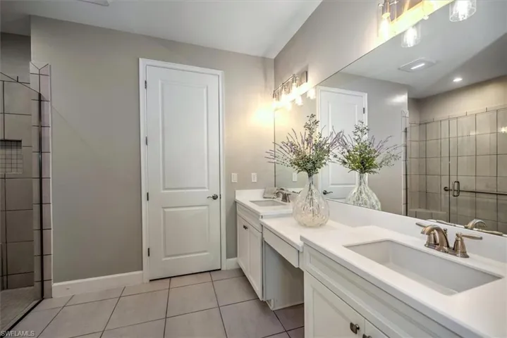 Bathroom featuring a sink, double vanity, a shower stall, and tile patterned floors
