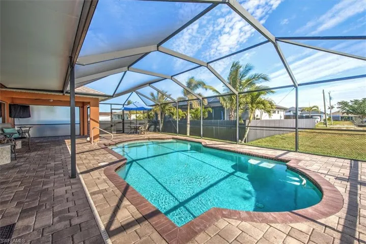 View of pool featuring a lawn, a patio, and glass enclosure