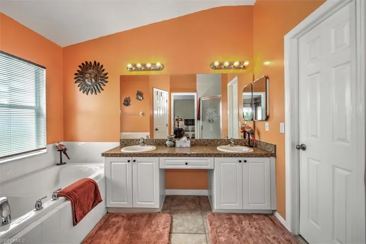 Bathroom with shower with separate bathtub, lofted ceiling, vanity, and tile patterned floors