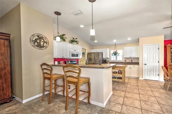Kitchen featuring decorative light fixtures, stainless steel appliances, kitchen peninsula, and white cabinets