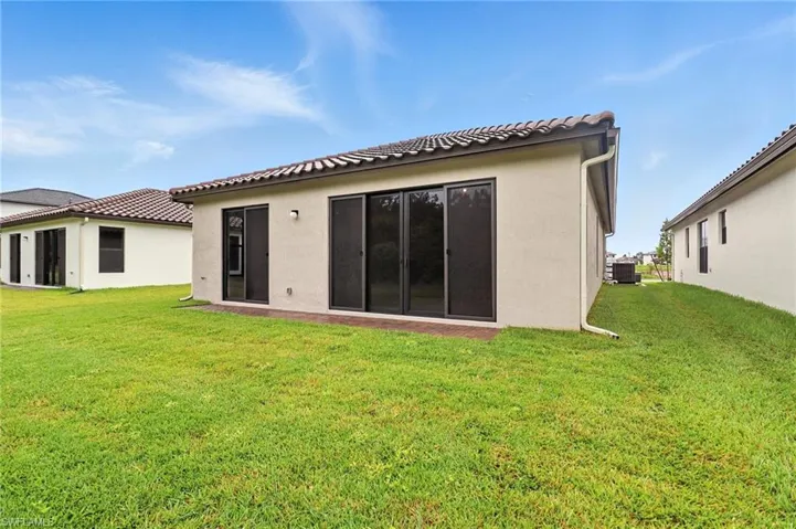 Rear view of property featuring a lawn and stucco siding
