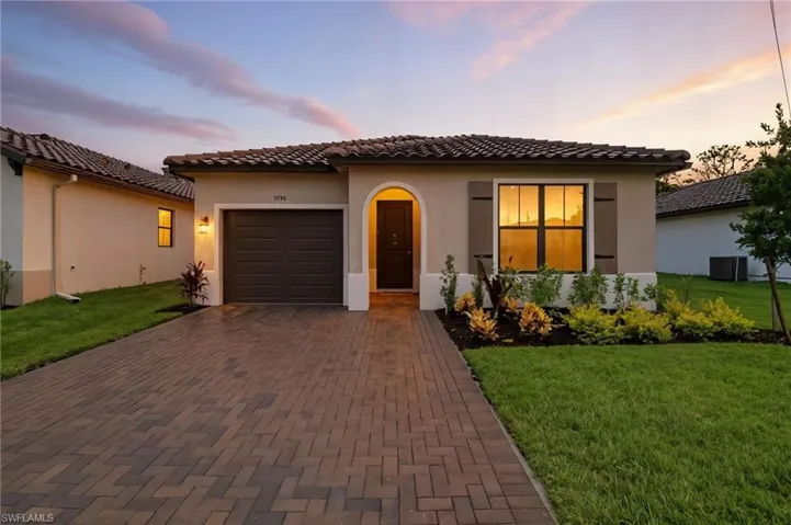 Mediterranean / spanish house featuring decorative driveway, stucco siding, a garage, a front yard, and a tiled roof