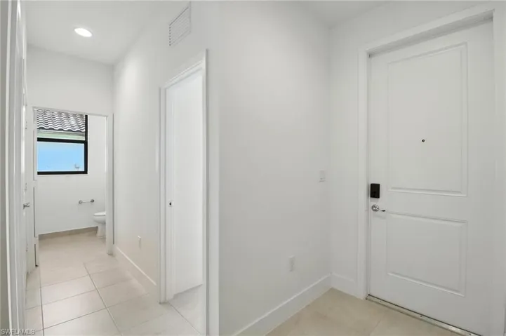 Corridor with light tile patterned flooring and recessed lighting