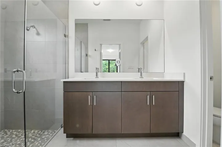 Full bath with double vanity, a stall shower, and tile patterned floors