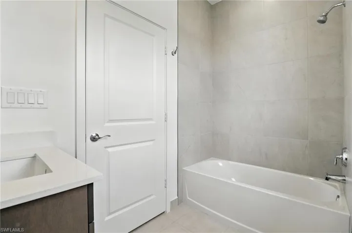 Bathroom with vanity, shower / washtub combination, and tile patterned flooring