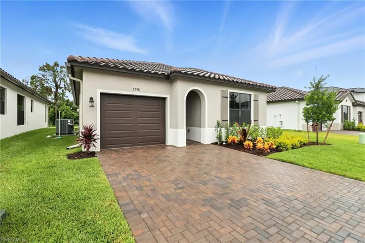 Mediterranean / spanish home with decorative driveway, a garage, a front yard, stucco siding, and a tiled roof