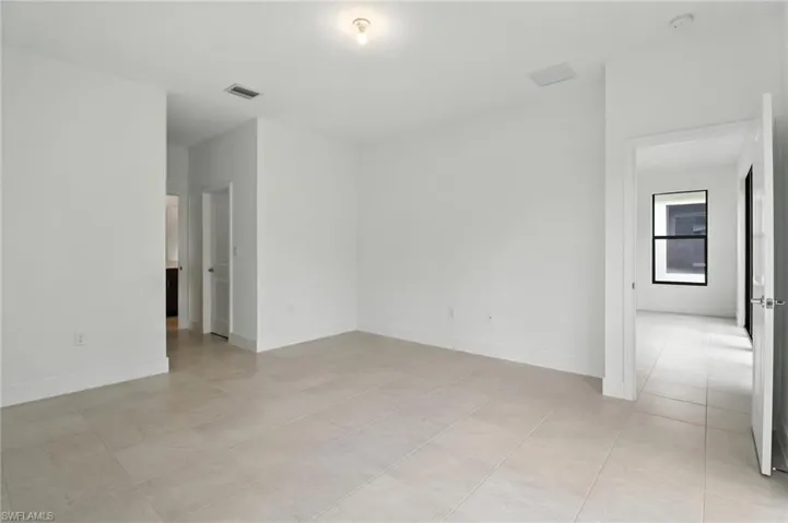 Empty room with a smoke detector and light tile patterned floors