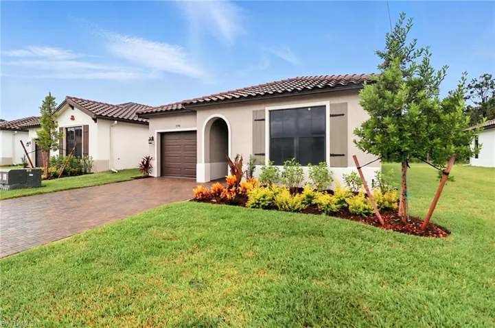 Mediterranean / spanish-style house with decorative driveway, an attached garage, a front yard, stucco siding, and a tile roof