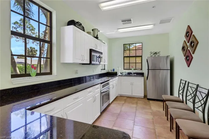 Kitchen featuring stainless steel appliances, white cabinets, dark stone counters, and light tile patterned floors