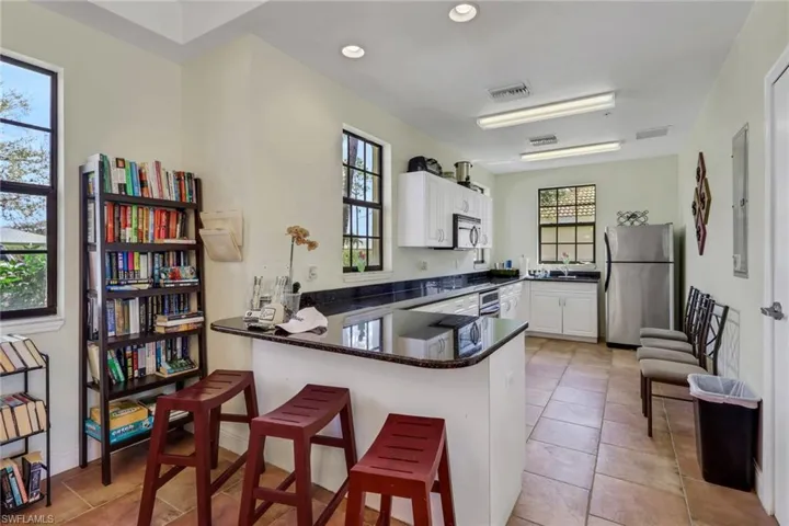 Kitchen featuring white cabinetry, a peninsula, stainless steel appliances, a kitchen breakfast bar, and dark stone counters