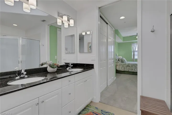 Ensuite bathroom featuring double vanity, light colored carpet, a stall shower, recessed lighting, and a closet