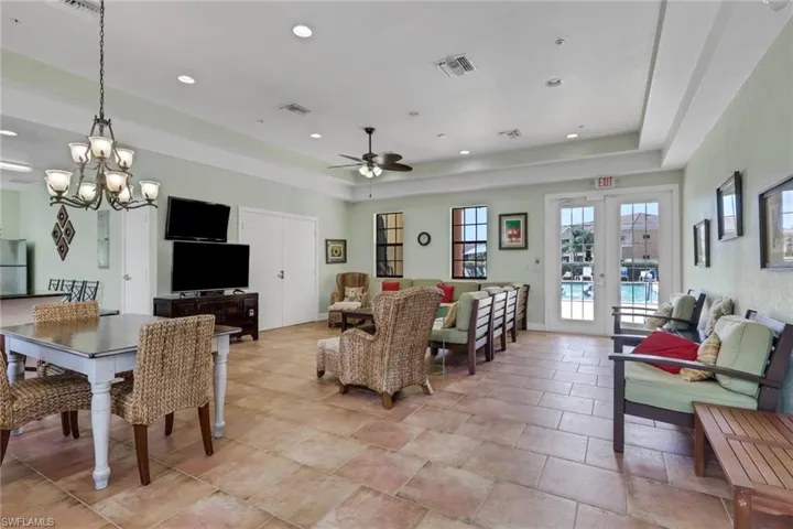 Living area with a tray ceiling, ceiling fan, a chandelier, and french doors