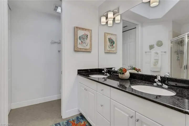 Full bathroom with double vanity, a stall shower, and light tile patterned floors