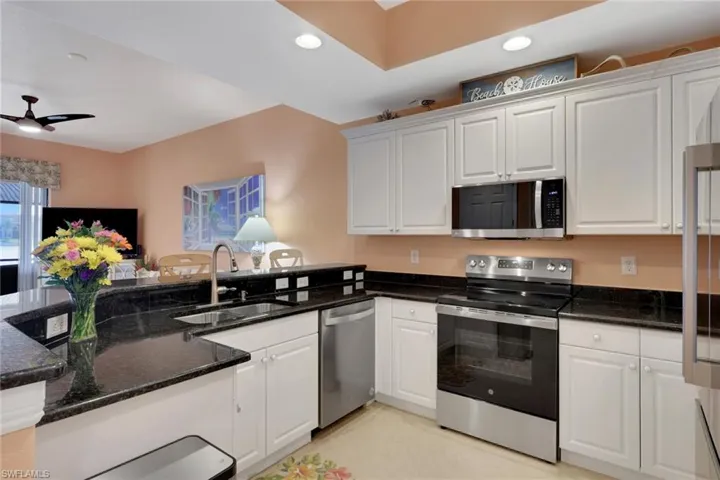Kitchen with stainless steel appliances, white cabinets, dark stone countertops, recessed lighting, and ceiling fan