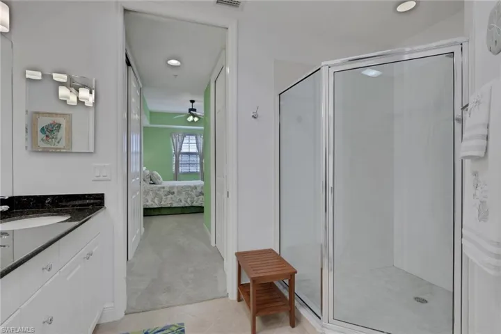 Ensuite bathroom featuring vanity, light colored carpet, a stall shower, and recessed lighting