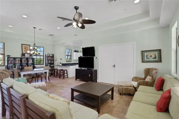 Living area with a raised ceiling, a chandelier, ceiling fan, and light tile patterned floors