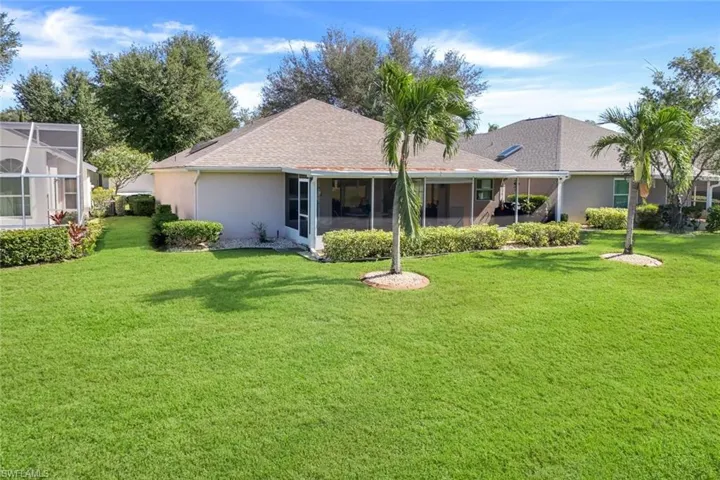 Rear view of property with a sunroom, a yard, a shingled roof, and stucco siding