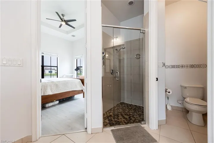 Full bathroom with ensuite bath, a stall shower, light tile patterned floors, and ceiling fan
