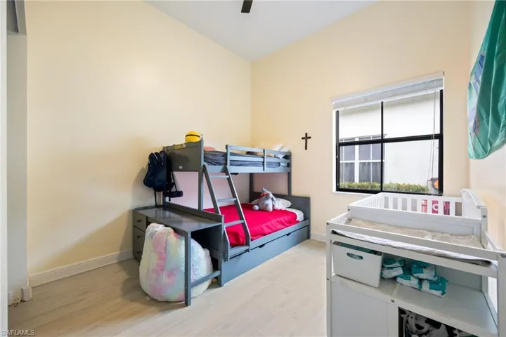 Bedroom with light wood-style floors, a ceiling fan, and vaulted ceiling
