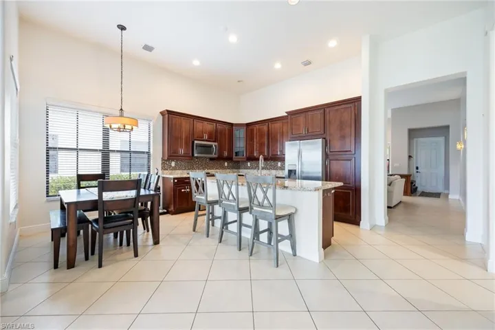 Kitchen with a kitchen breakfast bar, glass insert cabinets, decorative backsplash, a kitchen island, and light stone counters