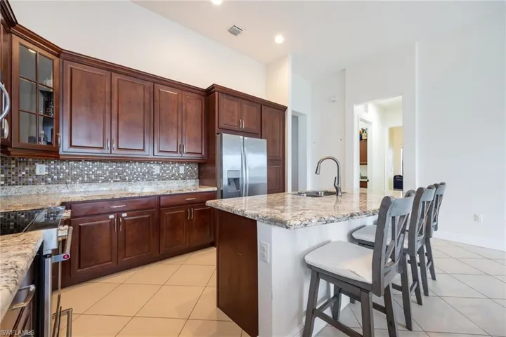 Kitchen with light tile patterned floors, a breakfast bar, glass insert cabinets, and stainless steel appliances