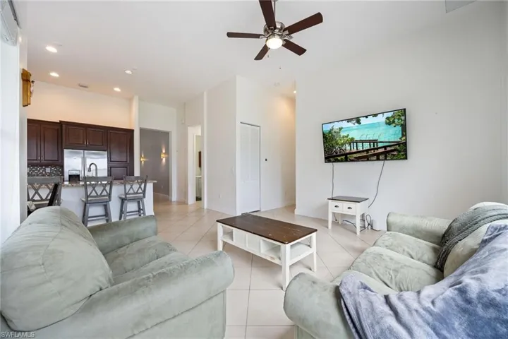 Living area featuring recessed lighting, ceiling fan, light tile patterned floors, and a high ceiling