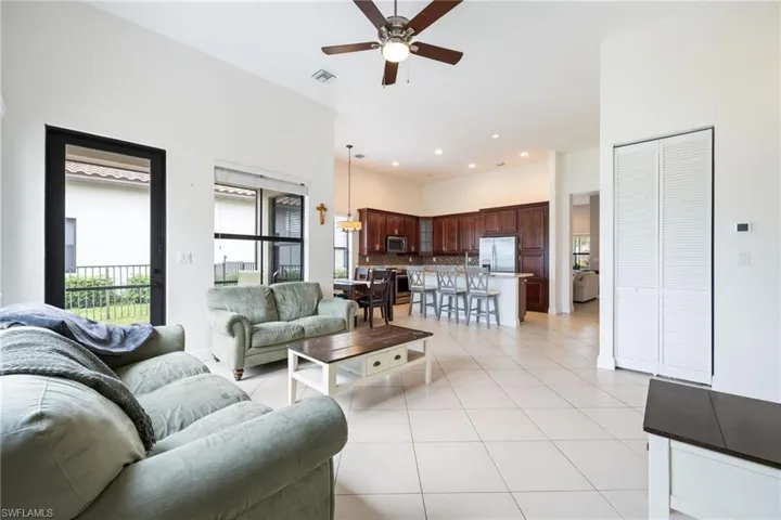Living area with light tile patterned floors, a high ceiling, a ceiling fan, and recessed lighting