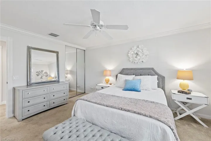 Carpeted bedroom featuring baseboards, ornamental molding, visible vents, and a closet