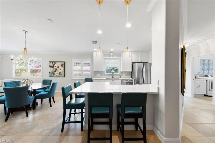 Kitchen with stainless steel appliances, light countertops, visible vents, a kitchen bar, and tasteful backsplash