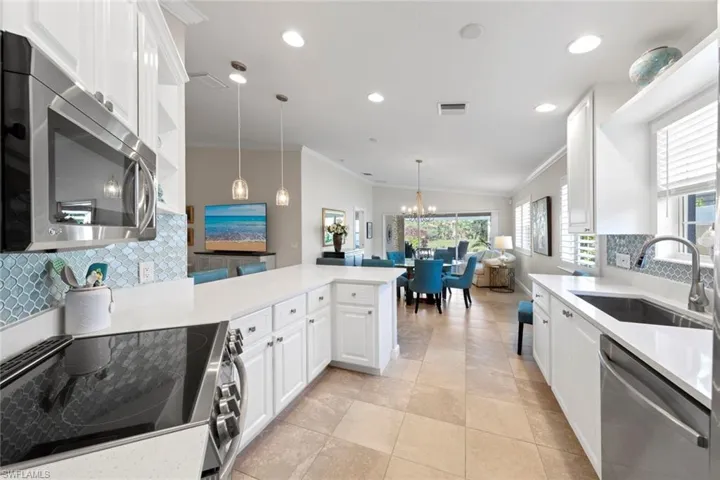 Kitchen featuring crown molding, tasteful backsplash, a sink, stainless steel appliances, and a peninsula