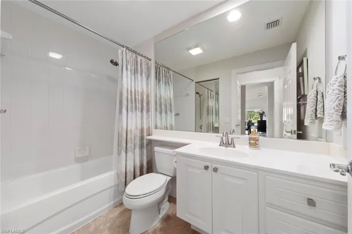 Full bathroom featuring vanity, shower / bathtub combination with curtain, toilet, tile patterned flooring, and visible vents
