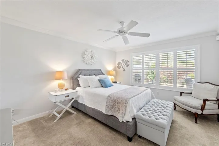 Carpeted bedroom with a ceiling fan, baseboards, and crown molding