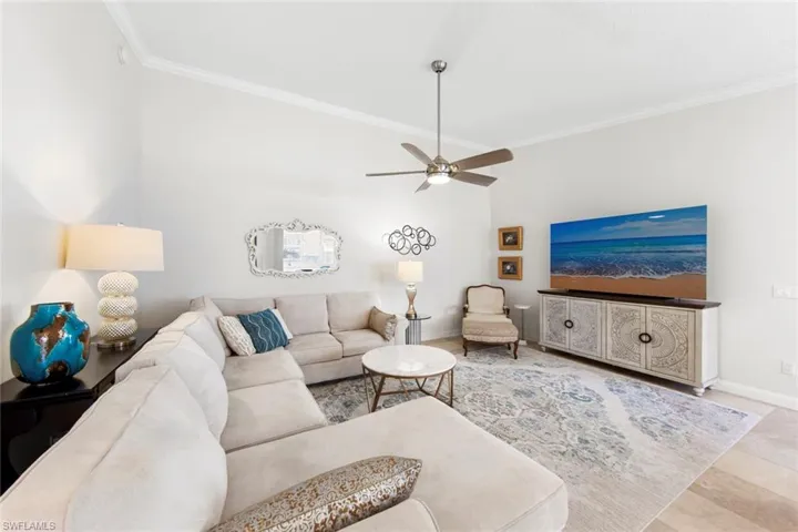 Living room with baseboards, ceiling fan, and crown molding