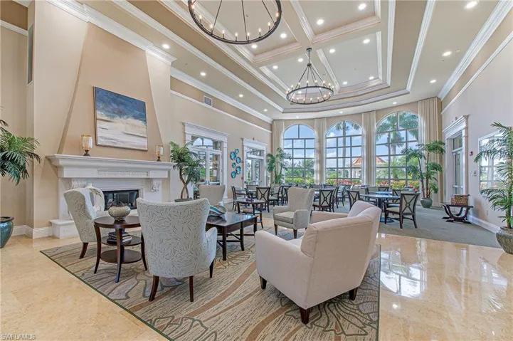 Living room with crown molding, recessed lighting, a high ceiling, a high end fireplace, and a notable chandelier