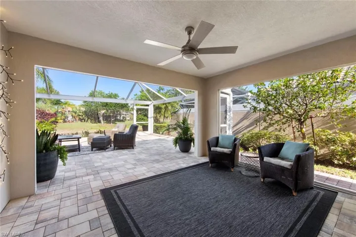 View of patio featuring glass enclosure, ceiling fan, and an outdoor hangout area