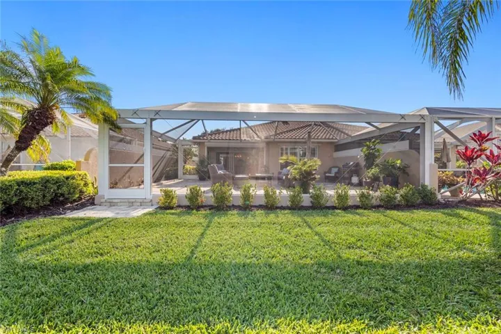Back of house with glass enclosure, a yard, a patio area, and stucco siding