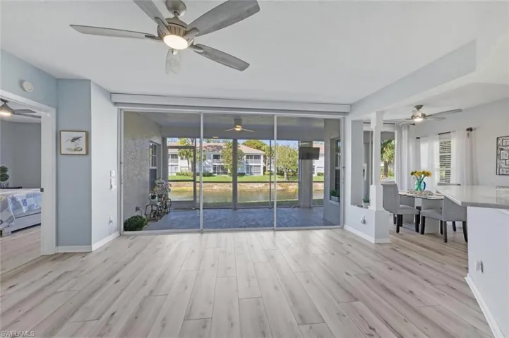 Unfurnished living room featuring ceiling fan, light wood-style floors, and a water view