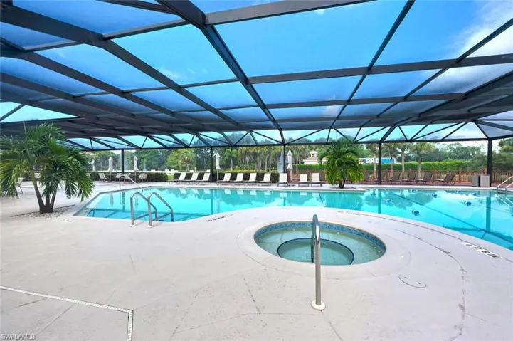Community pool featuring a hot tub, a patio area, and glass enclosure