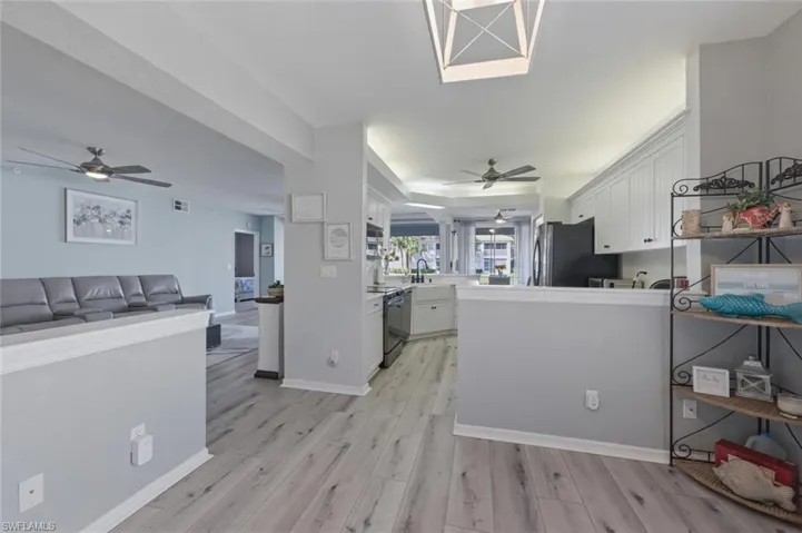 Kitchen with a ceiling fan, white cabinets, and open floor plan