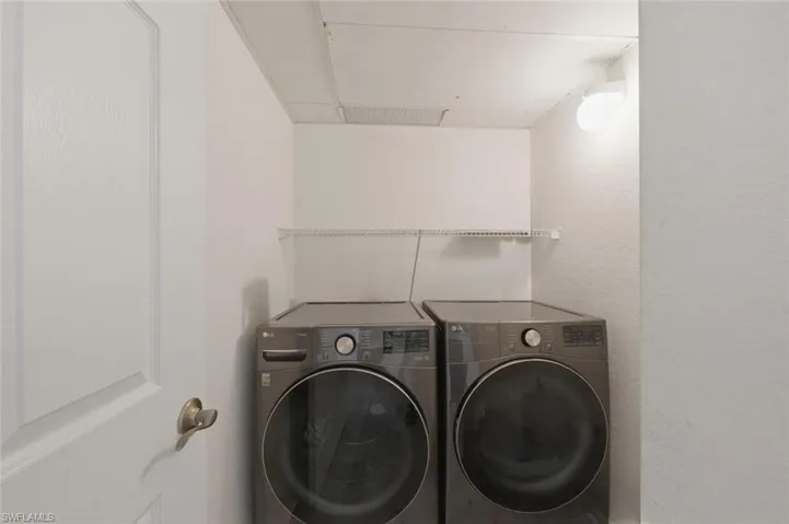Laundry room featuring washer and clothes dryer and a textured wall