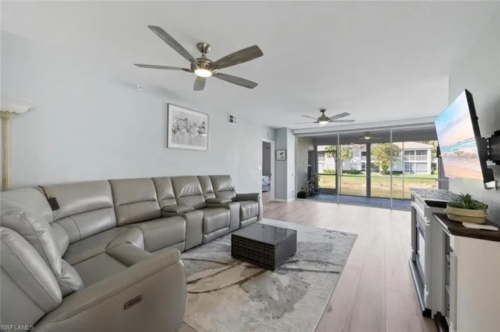 Living room featuring light wood-type flooring, a ceiling fan, and expansive windows